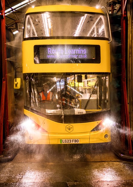 A yellow bus going through a bus wash.
