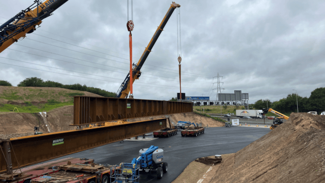 The beams being lowered into the worksite next to the M62