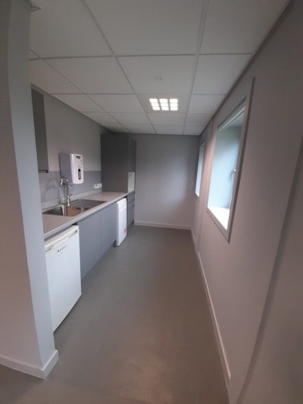 Refurbished kitchen area with grey cupboards, white appliances and a stainless steel sink.