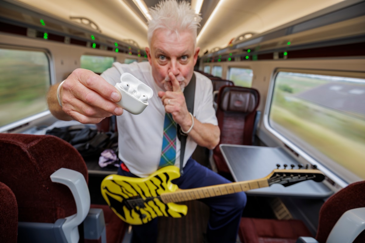 Robb Weir onboard LNER train with guitar calling for quiet
