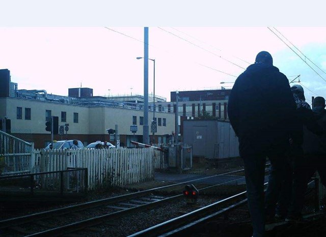 People coming off the platform and then heading towards the track by Grays level crossing