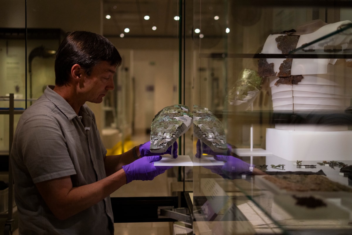 Dr Fraser Hunter installs the Roman arm guard in the Early People gallery at the National Museum of Scoltand. Image copyright Duncan McGlynn (3)