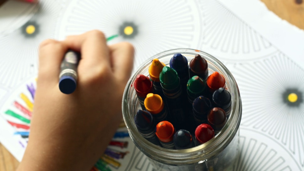 Child's hand holding crayons