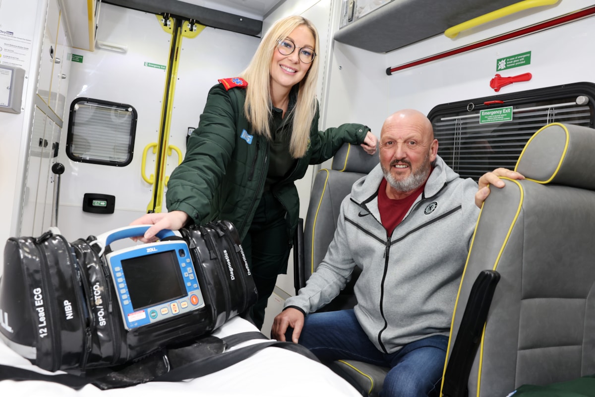 Graham Avery sat in an ambulance with a female paramedic stood beside him with a defibrilator.