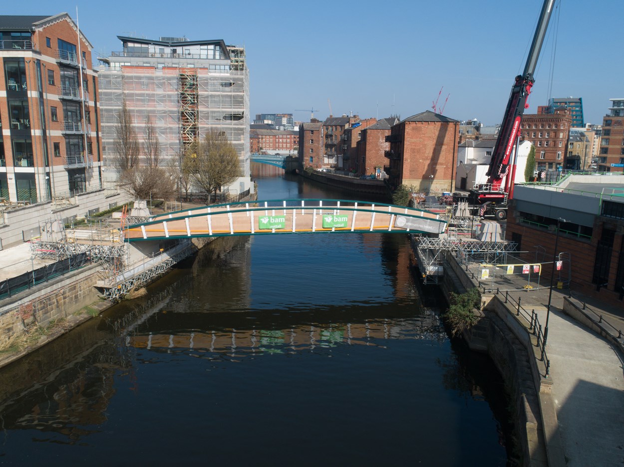 David Oluwale bridge installation: The David Oluwale bridge is lifted into place over the River Aire in Leeds. Engineers working on the David Oluwale bridge completed one of the project’s major milestones over the weekend, with cranes carefully placing the 40 tonne structure over the river where it will connect Sovereign Street to Water Lane. Credit BAM Nuttall.