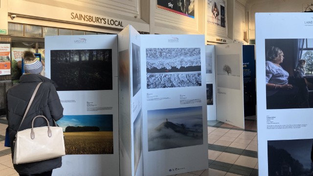 Passenger viewing the Landscape Photographer of the Year gallery on display at Leeds station Network Rail