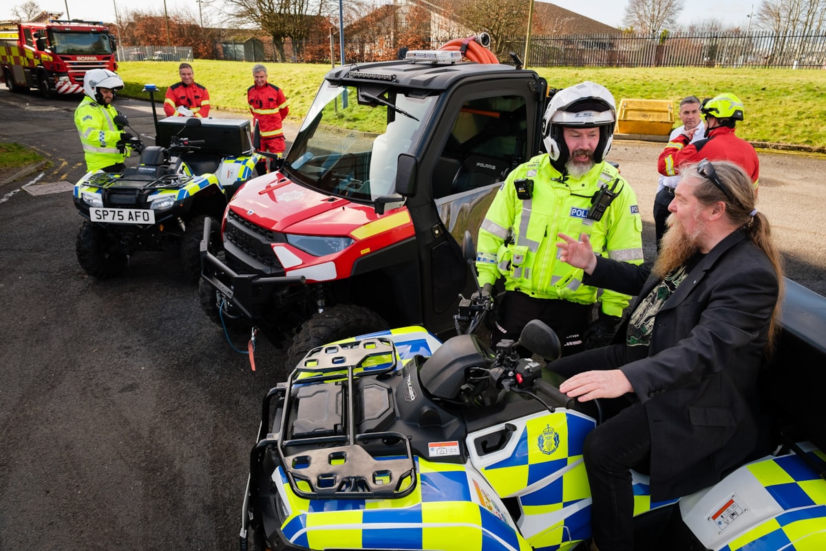 Emergency responders in hi viz uniforms standing next to two police quad bikes and one small fire rescue vehicle. Councillor Todd is sitting on one of the quad bikes.