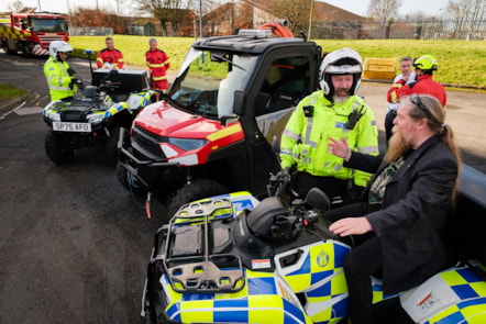Emergency responders in hi viz uniforms standing next to two police quad bikes and one small fire rescue vehicle. Councillor Todd is sitting on one of the quad bikes.