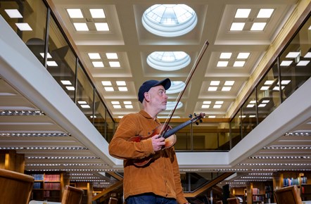 Fiddler Aidan O'Rourke in the General Collections Reading Room at the National Library of Scotland's George IV Bridge building. Credit: Neil Hanna