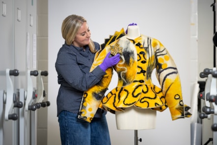 Curator Lisa Mason examines a yellow jacked designed by Jean Muir. Photo © Duncan McGlynn (2)