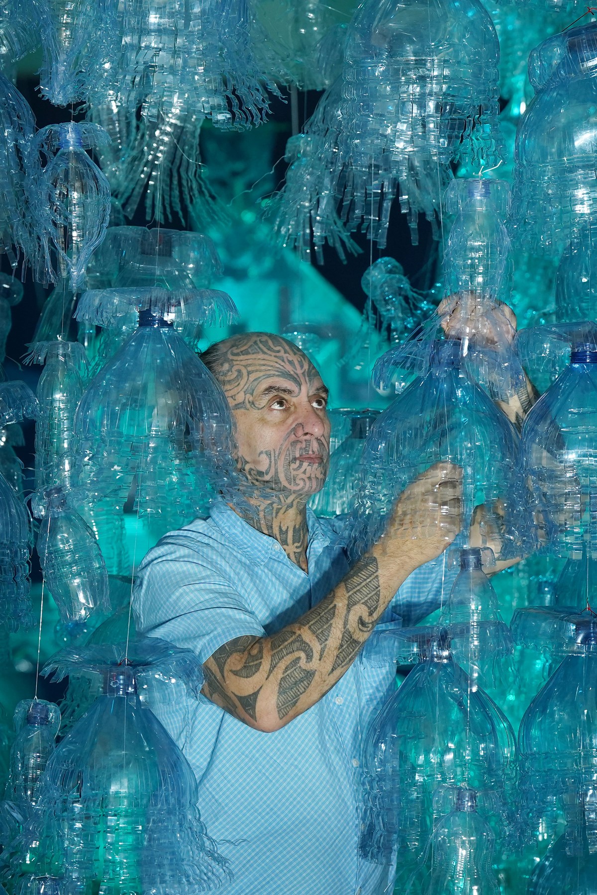 Artist George Nuku puts the finishing touches to the installation of the artwork Bottled Ocean 2123, an imagined underwater landscape made from recycled plastic. The work will go on show in the exhibition Rising Tide: Art and Environment in Oceania, which opens on August 12 at the National Museum of Scotland. Image credit: Stewart Attwood