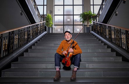 Fiddler Aidan O'Rourke on the main stairs of the foyer in the National Library of Scotland's George IV Bridge building. Credit: Neil Hanna