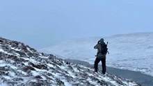 A NatureScot stalker scans the snowy landscape ©NatureScot