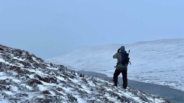 A NatureScot stalker scans the snowy landscape ©NatureScot