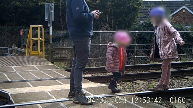 Parent on phone while young children use live tracks as a playground: Parent on phone while young children use live tracks as a playground