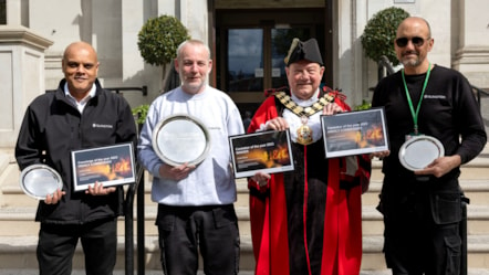 Three men wearing Islington Council uniforms stand smiling in front of Islington Town Hall with The Mayor of Islington, Councillor Gary Heather