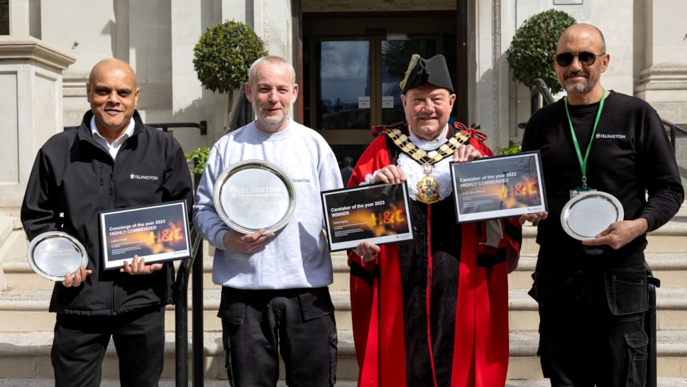 Three men wearing Islington Council uniforms stand smiling in front of Islington Town Hall with The Mayor of Islington, Councillor Gary Heather