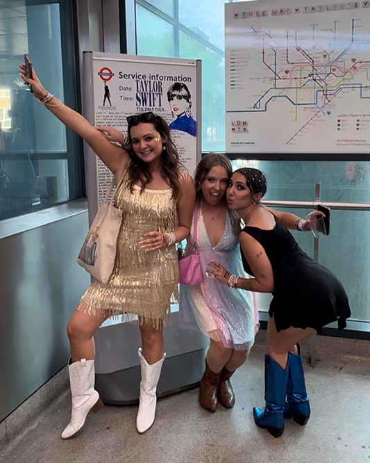 TfL Image - Fans attending Taylor Swift's The Eras Tour pose in front of TfL's Swift-themed Tube map at Wembley Park Tube station