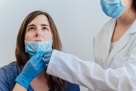 Example of lady receiving swab test from figure dressed in PPE