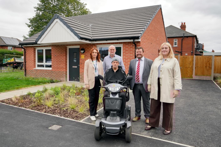 Ambertons 5: Pictured left to right: Zoe Griffiths (senior project manager, West Yorkshire Combined Authority), Dan Miller (operations director, Wates), Alan Neal (senior project manager, Wates) and Councillor Jess Lennox (Leeds City Council's executive member for housing) with, front, tenant Paul Bennett.