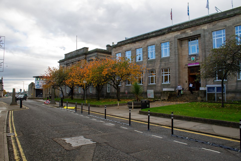 An autumnal, external image of Moray Council's HQ in Elgin, which shows leaves yellowing on the five small trees that line the avenue.