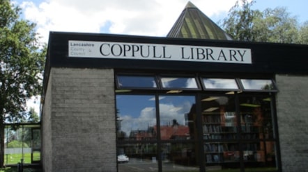 The outside of Coppull library has large windows and white bricks with a white sign and the words 