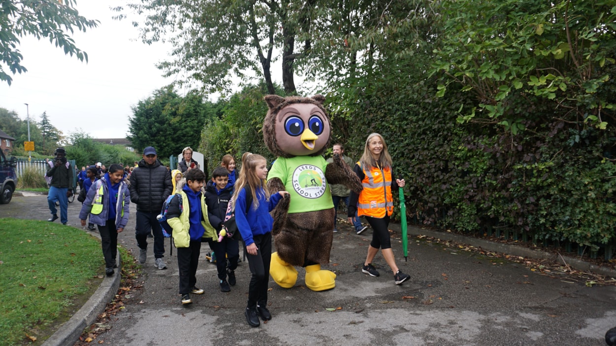 Safe and sustainable travel mascot, Arlo the Owl, guiding pupils from Ireland Wood primary school across the School Street: Safe and sustainable travel mascot, Arlo the Owl, guiding pupils from Ireland Wood primary school across the School Street