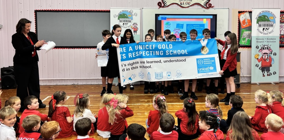 Children from the school unviel the gold banner with Head Teacher Mrs Kelly