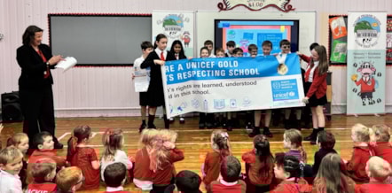 Children from the school unviel the gold banner with Head Teacher Mrs Kelly