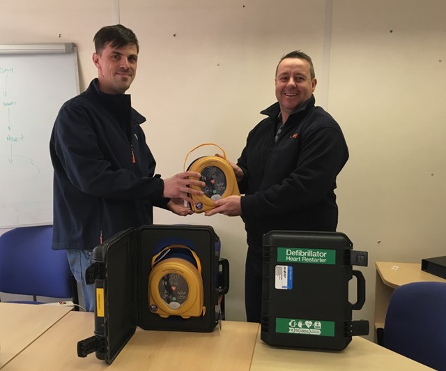 Matthew Oliver, senior technical officer (left), receives a defibrillator for Swansea depot, from David John, project manager (right).