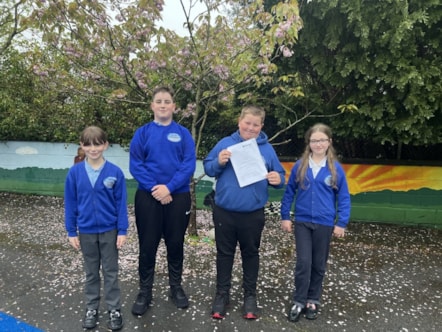 Four Ysgol Casblaidd pupils with their Estyn report