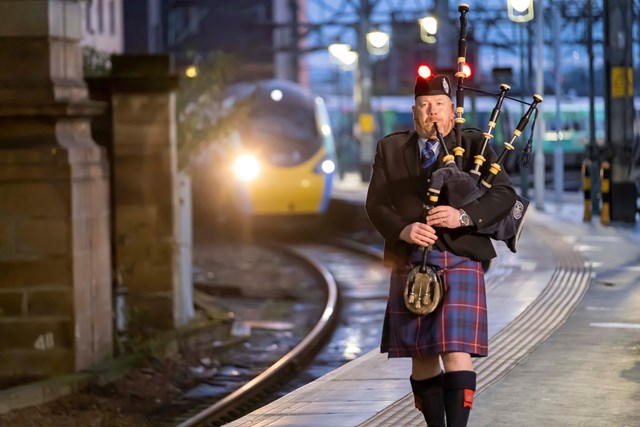 A piper welcomes the 'Climate Train' to Glasgow Central on Saturday