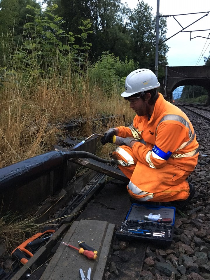 Orange army member repairs damage caused by copper thieves on West Coast main line in Staffordshire