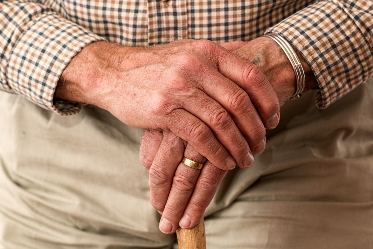 man with hands on walking stick