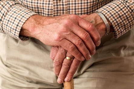 older man with hands on walking stick