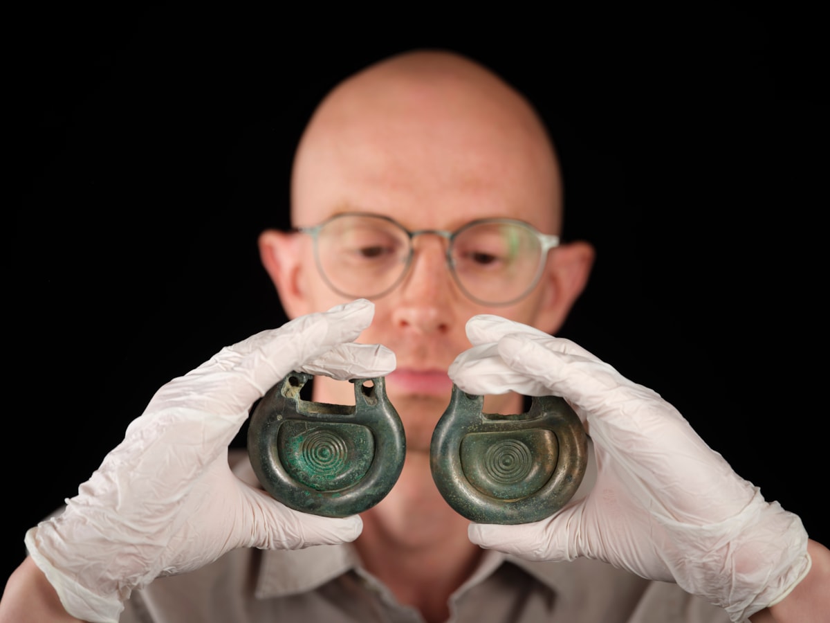 Curator Matthew Knight holds bronze fittings from the Peebles Hoard. Photo © Duncan McGlynn
