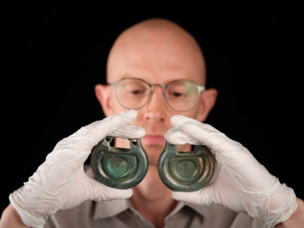 Curator Matthew Knight holds bronze fittings from the Peebles Hoard. Photo © Duncan McGlynn