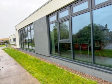 Exterior of Cullen Primary School showing a row of large, dark-framed windows along the refurbished building.