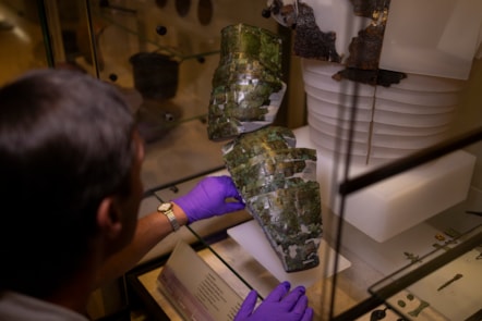 Dr Fraser Hunter installs the Roman arm guard in the Early People gallery at the National Museum of Scoltand. Image copyright Duncan McGlynn (2)