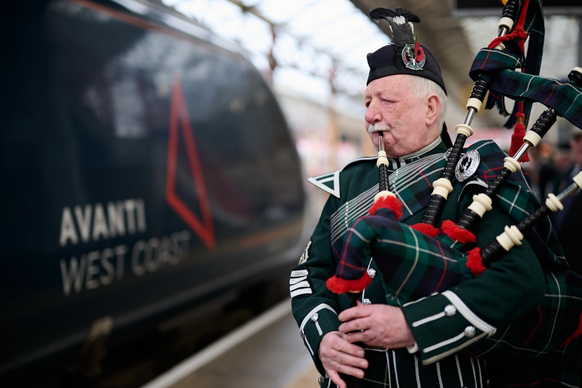 A bagpiper sends off the poppy wreath on its journey by train to London