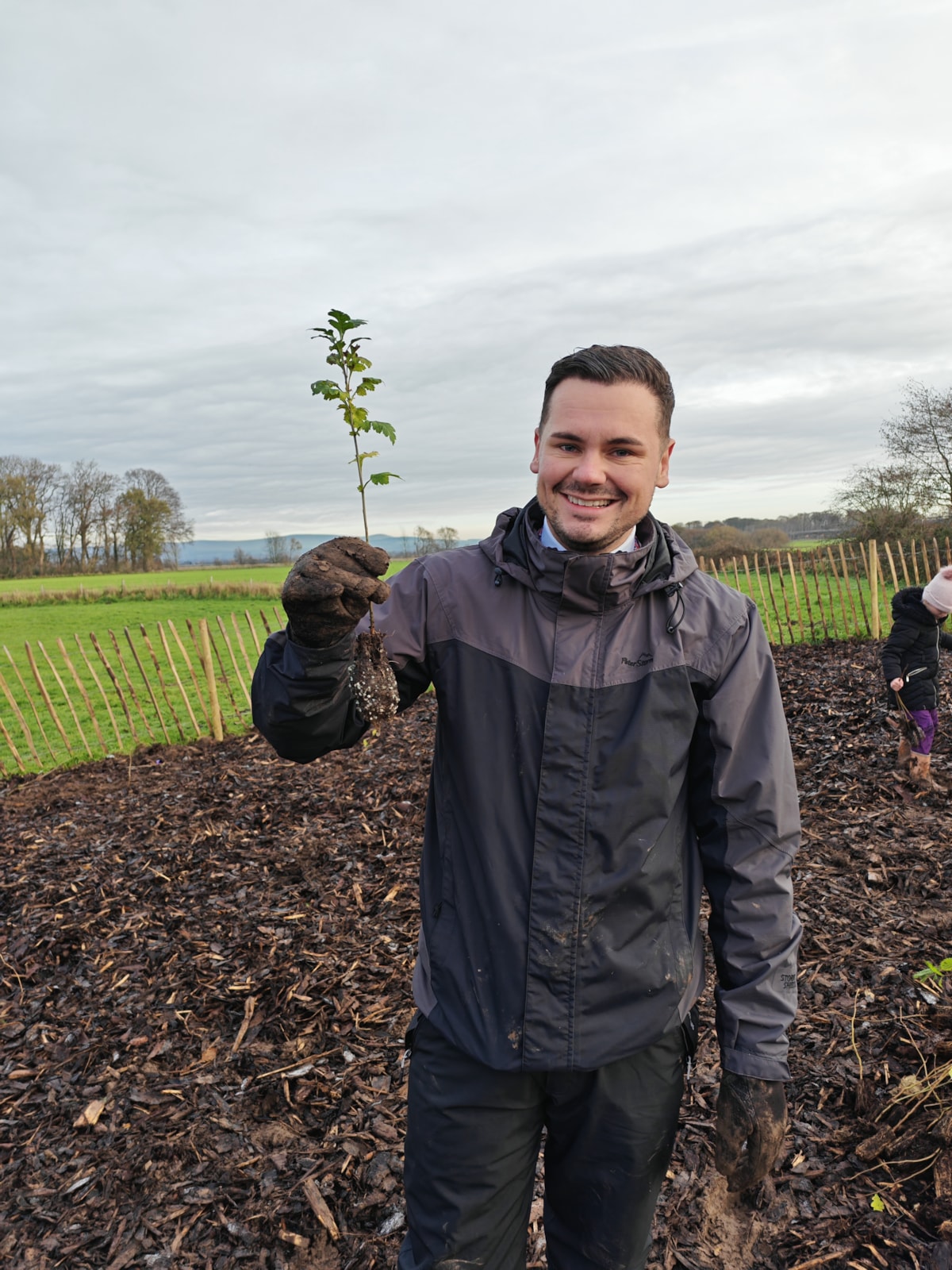 Councillor Joshua Roberts holding one of the saplings ready to plant