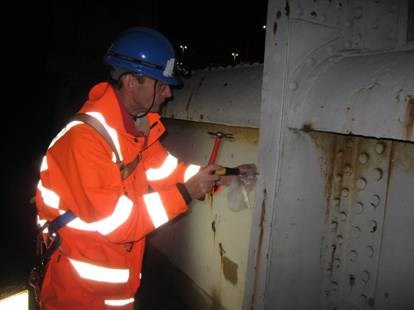 Expert taking samples from bridge to analyse paint system