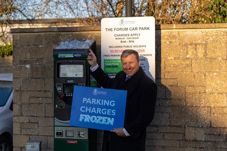 Cllr Mike Evemy announcing freeze to parking charges in 2023. Cllr Evemy is holding a sign that reads 'Parking Charges Frozen'.