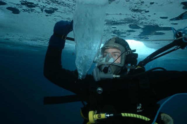 Diver under ice looking a a sea brine column. John Withers.