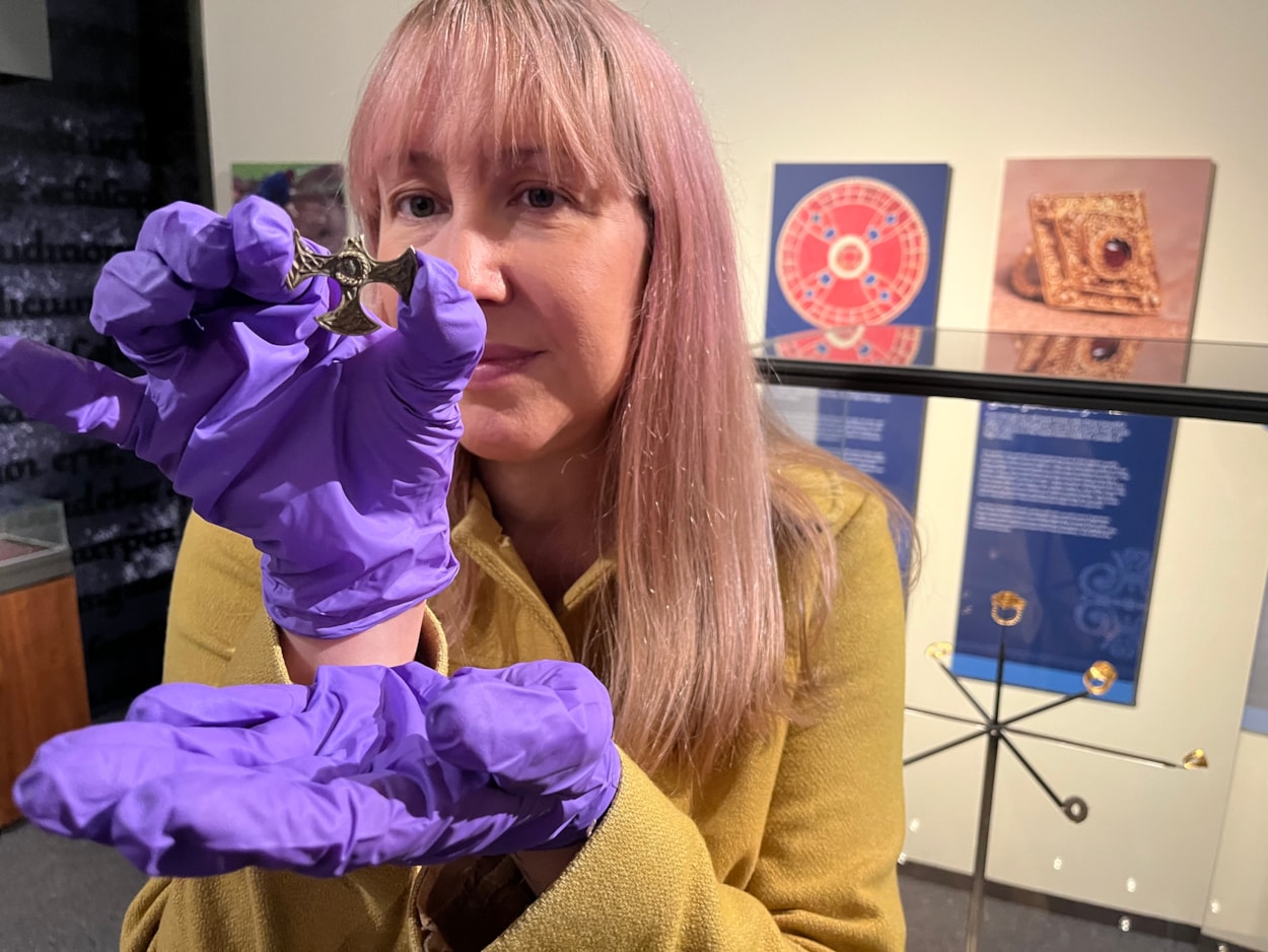 Saxon cross display: Curator of archaeology Kat Baxter with the ancient Saxon cross now on display at Leeds City Museum.
Believed to have once been a prestigious badge of office and a sign of religious identity, the silver, gilded pendant was discovered by a metal detectorist, with one of its four arms broken, and its central stone missing.
Newly created drawings, penned by archaeological illustrator John Prudhoe, show how the complete cross could have looked with its thin layer of gold leaf shining and a beautiful central garnet.