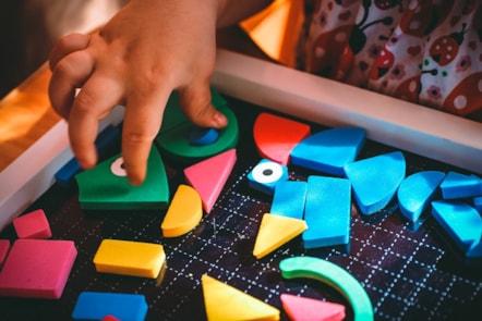 the hand of a child playing with a colourful puzzle