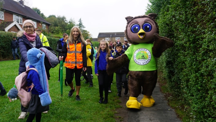 Leeds City Council safe and sustainable travel mascot, Arlo the Owl, guiding pupils from Ireland Wood primary school across the School Street: Image shows safe and sustainable travel mascot, Arlo the Owl, guiding pupils from Ireland Wood primary school across the School Street