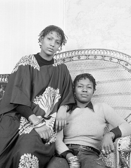 Lia Obi and Olive Morris: Anti-discrimination campaigner, women’s and squatter’s rights activist, Olive Morris (right) with friend Lia Obi posing in a Huey Newton, American Black Panther style chair. Morris was a leading member of the Brixton Black Women’s Group, Organisation of African and Asian Descent Group and the British Black Panthers.
