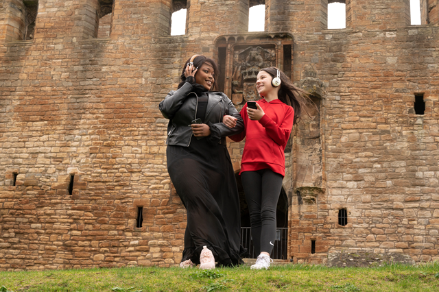 Linlithgow Scots Audio Guide: Laura Lovemore, a professional Scottish actor who provides the voice of Margaret More, one of the women known in the records as the ‘Moorish Lassies’, listening to the new Scots audio guide at Linlithgow Palace with Martha who voices the young Princess Elizabeth, daughter of James VI & Anna of Denmark.