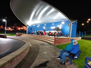 valleygardens: A classical concert on stage at Withernsea Valley Gardens at night. Two people sit on a bench in the foreground